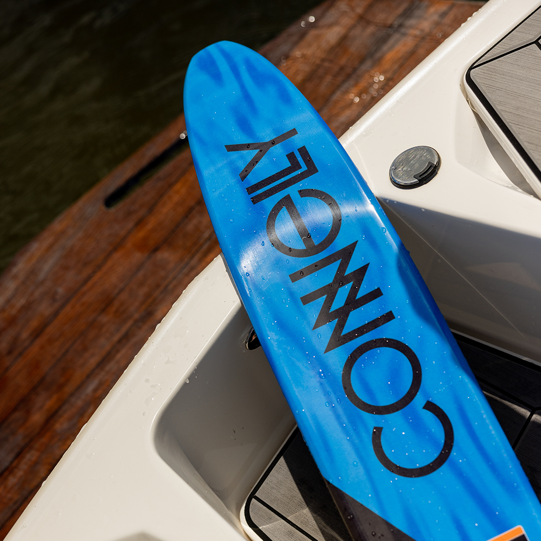 Lifestyle shot of the 2024 Connelly V ski, resting on a boat with a blue and black design and bold Connelly text.