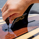 A person adjusts the fin on the Big Easy wakesurfer, securing it with a screw and tool.