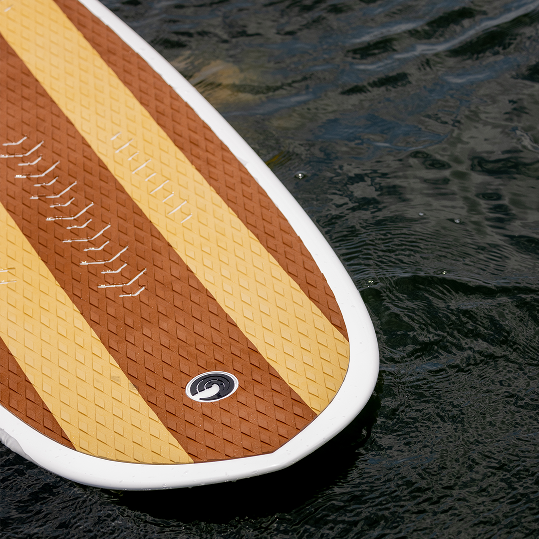 Close-up of the Big Easy wakesurfer’s textured deck with brown and yellow stripes floating on the water.