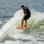 A wakesurfer rides the Big Easy wakesurfer on a wave, balancing effortlessly in the water.