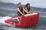 Two riders kneel and grip the front handles of the Big Easy 2 inflatable tube while riding the wake.