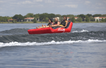 Three riders reclining on the Big Easy 3 tube as they glide over the water, with feet raised and secured by front handles.