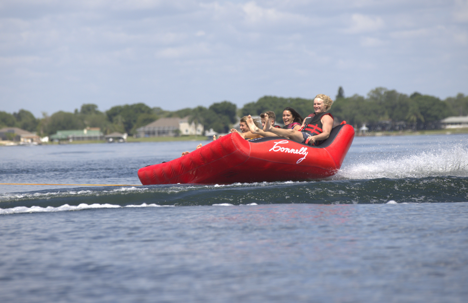 Big Easy 4 bouncing over a wake, with riders gripping tightly as the tube lifts into the air.