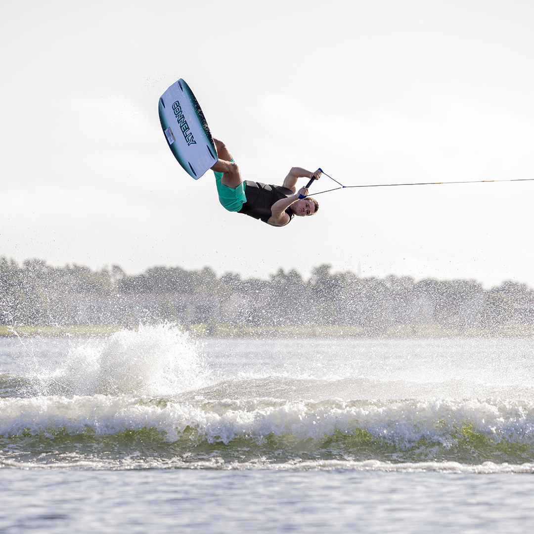 Wakeboarder performing an aerial trick over the water, holding the handle while riding the Bio wakeboard.