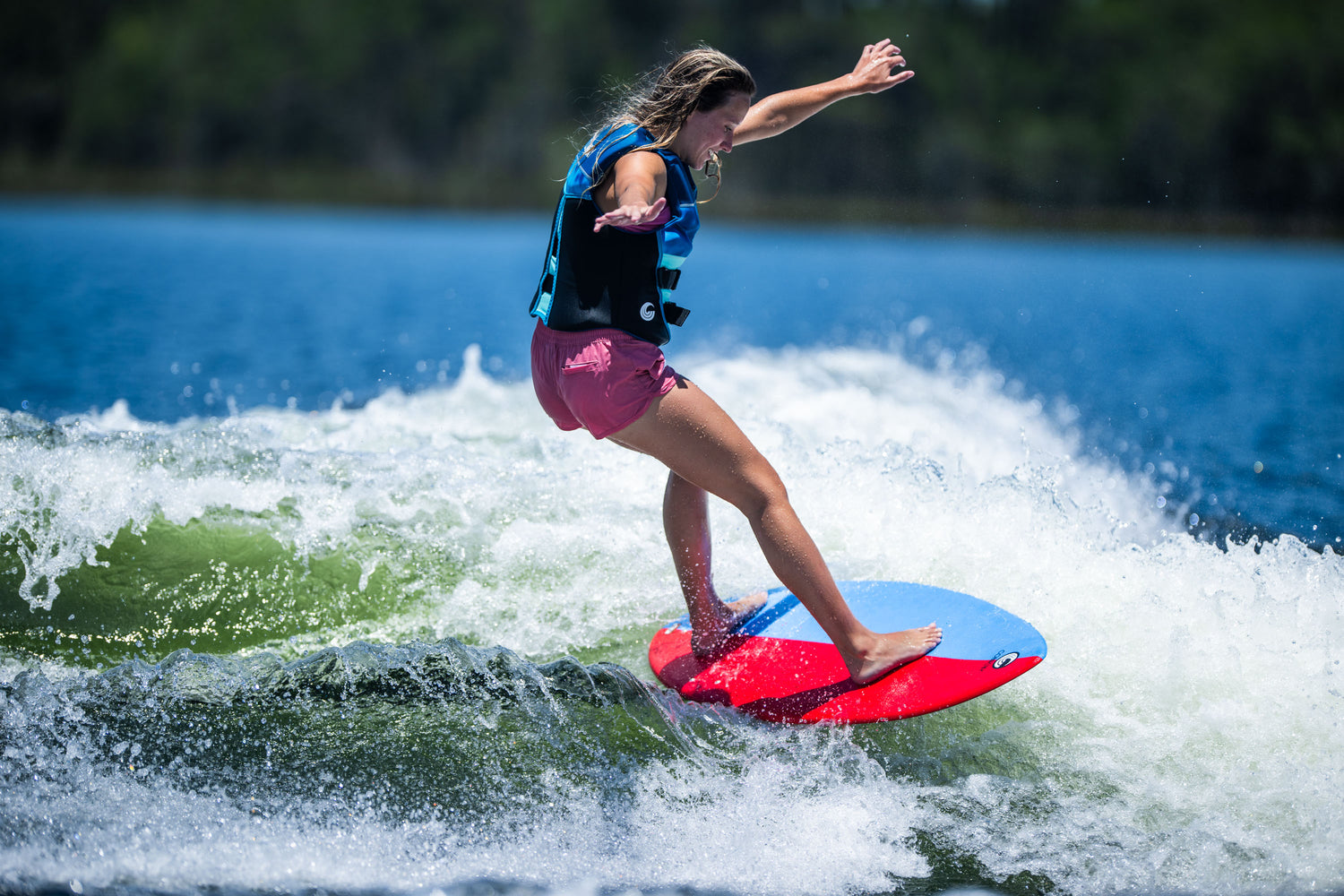 Young wakesurfer extending arms for balance while riding the DASH Kid's Board on a lake wave.