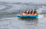 Fun 4 towable tube with four riders gripping handles and gliding across the water behind a boat.