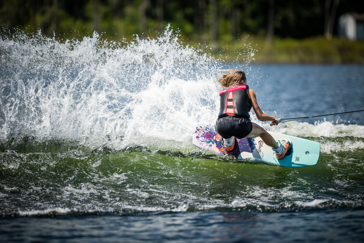 Action shot of a rider carving on the Wild Child wakeboard, creating a spray of water behind them.