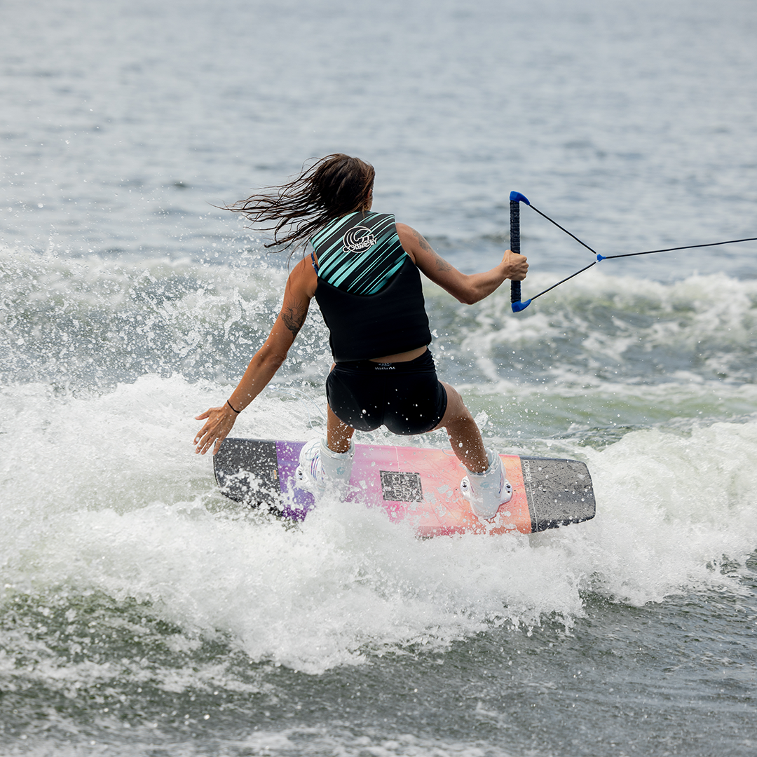 Wakeboarder rides 2024 Wild Child, carving through waves and creating a spray of white water.