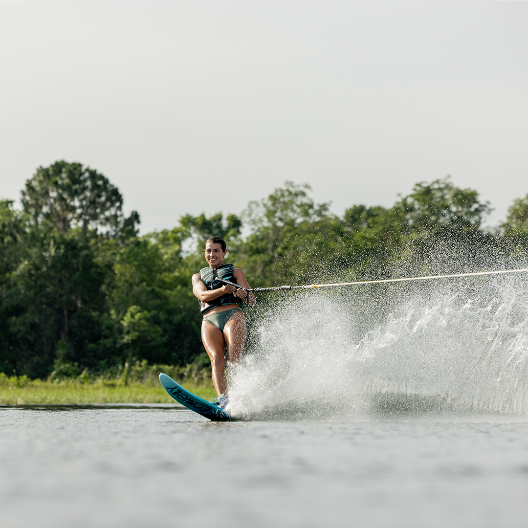 Action shot of woman carving through water on 2024 Women's Concept waterski, creating a wide spray.