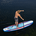 A man paddles on the Drifter iSUP, wearing shorts and a waist pack, gliding over calm water.