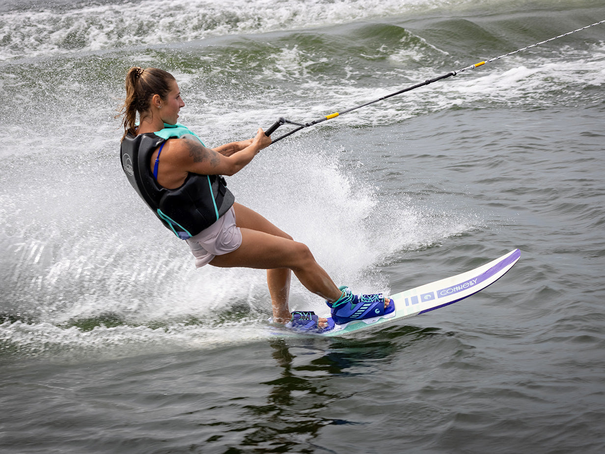 Female waterskier glides across the water using the Connelly Women's Aspect ski, creating a dynamic spray from the wake.